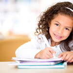 Cute little girl studying at the library and smiling