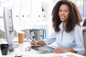 Smiling young afro-american office worker using drawing table, s