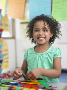 Portrait of smiling little girl assembling  puzzles in classroom