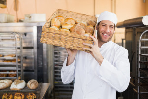 Baker holding basket of bread in the kitchen of the bakery