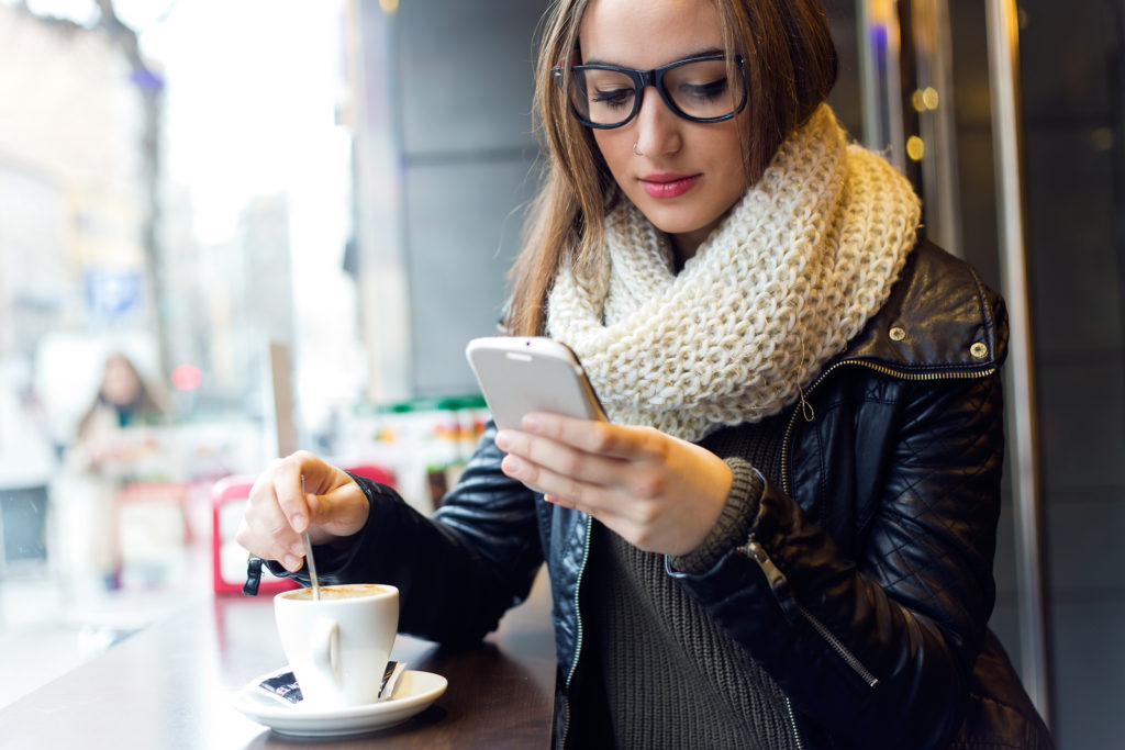 Beautiful Girl Using Her Mobile Phone In Cafe.